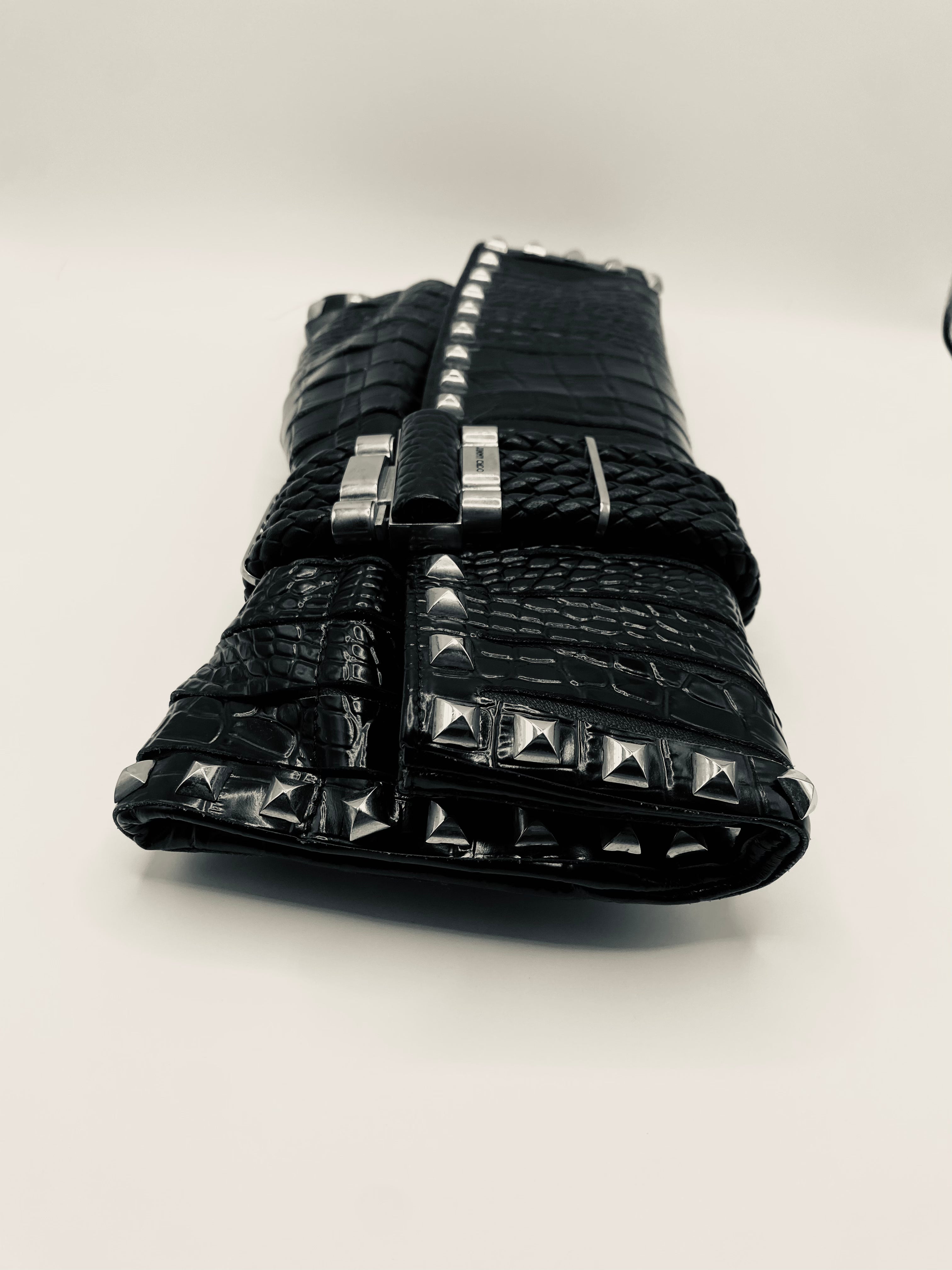 Black studded clutch bag on a light gray background